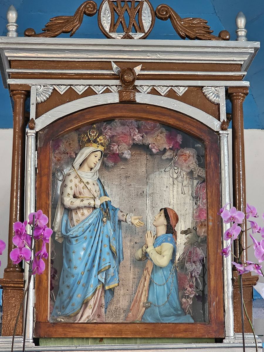 Detalhe da imagem de Nossa Senhora do Caravaggio em papel machê, mostrando a santa coroada estendendo a mão para a camponesa Joaneta ajoelhada